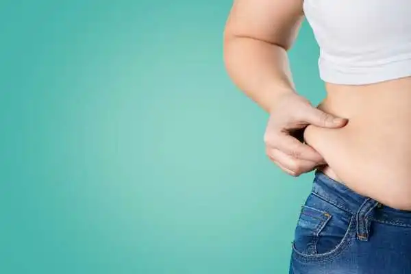 Image of woman pinching her love handles to show weight gain Oxfordshire